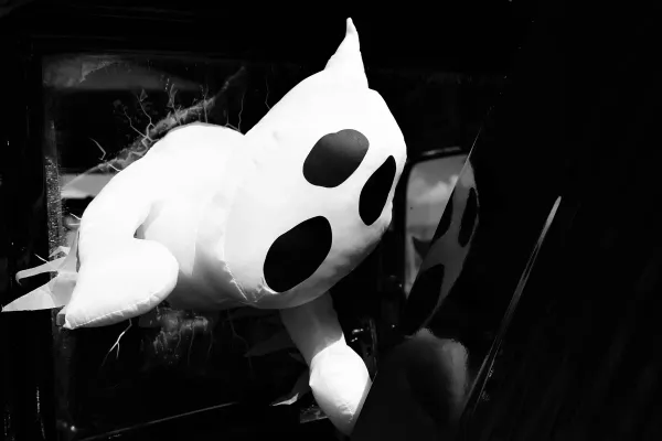 Black and White photo of a Ghost plushie emerging from a cracked mirror.