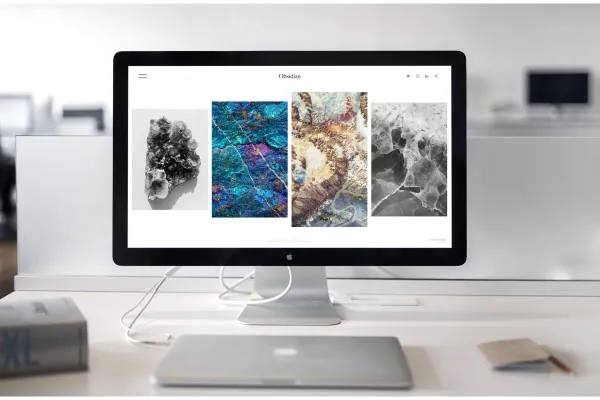 Macbook and iMac on a desk. The iMac screen displays a website.